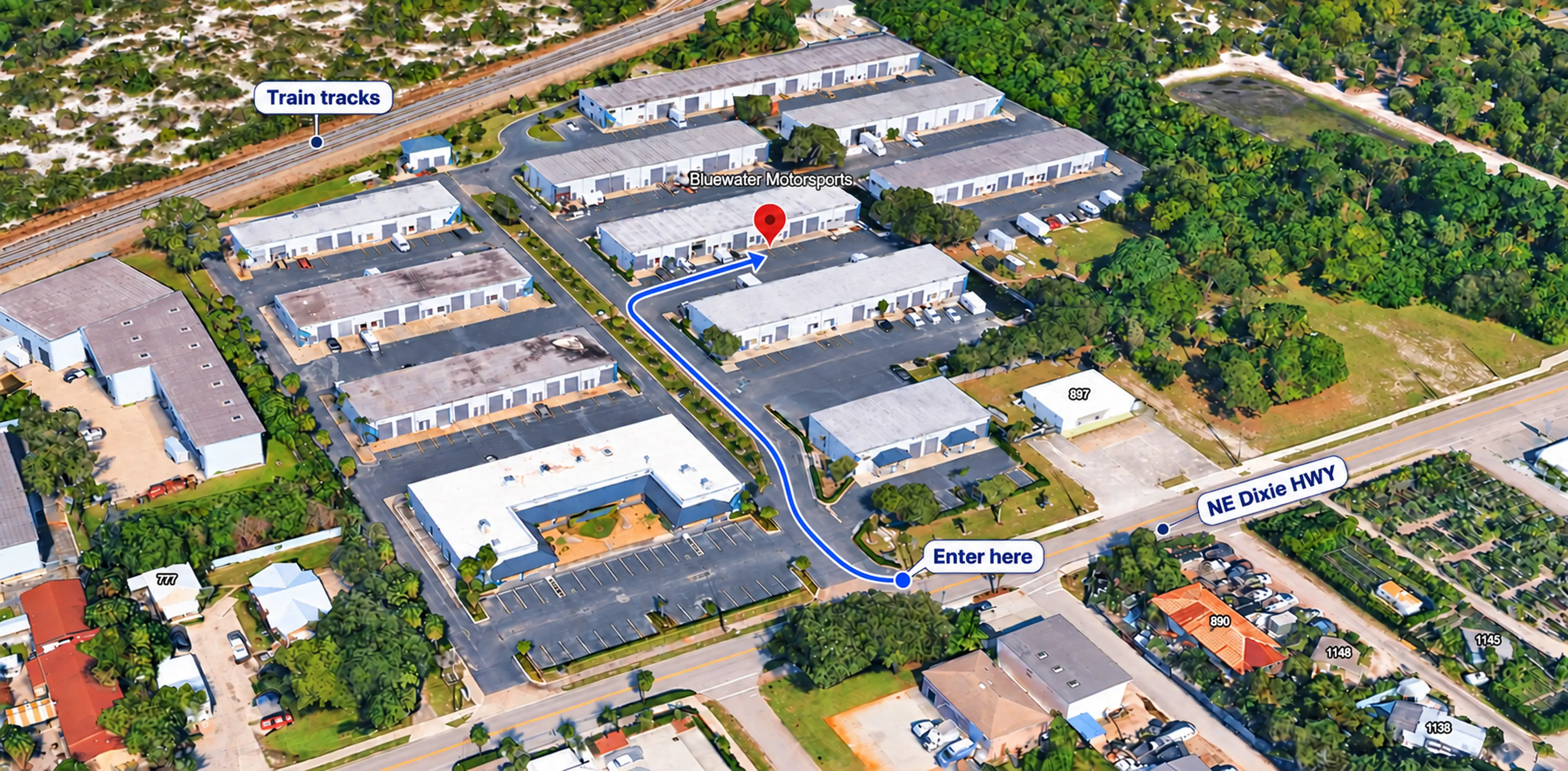 Aerial directions to Blue Water Motorsports: enter from NE Dixie Hwy, follow the blue route up the central driveway, and turn into the parking aisle in front of the shop marked by the red pin. Train tracks are labeled at the top.