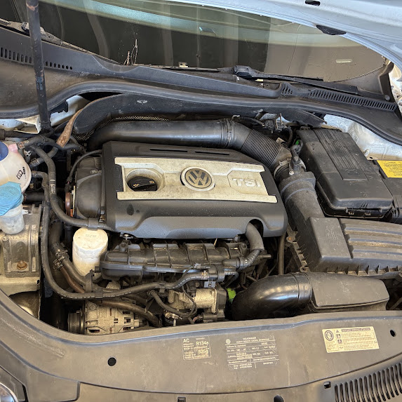 Volkswagen engine bay before cleaning, with dust visible on the engine cover and surrounding surfaces