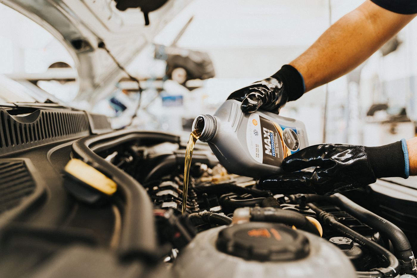 Oil being poured into a vehicle engine; illustrative service photography